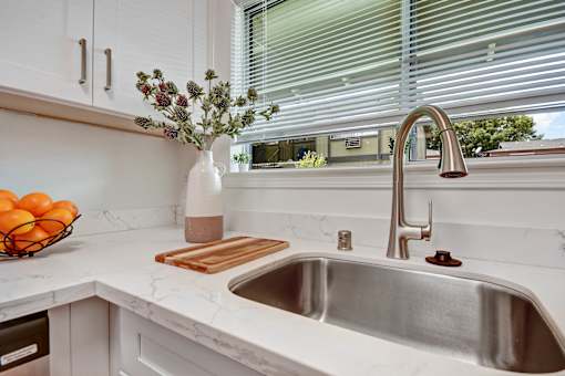 A kitchen with a white sink and a vase of flowers.