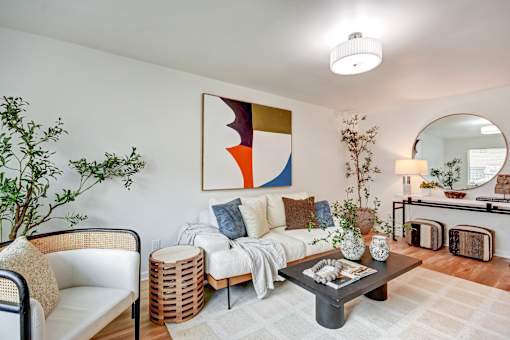 A living room with a white couch, a coffee table, and a large abstract painting on the wall.