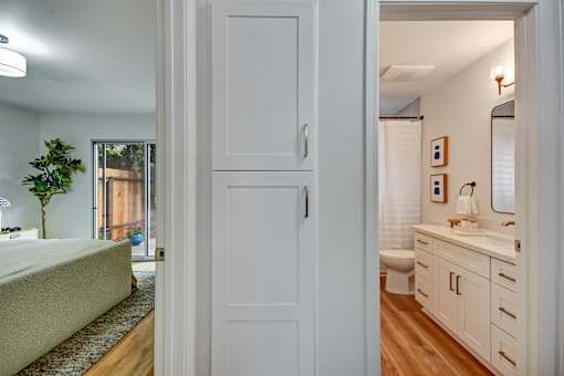 A white door opens to a bathroom with a sink and mirror.