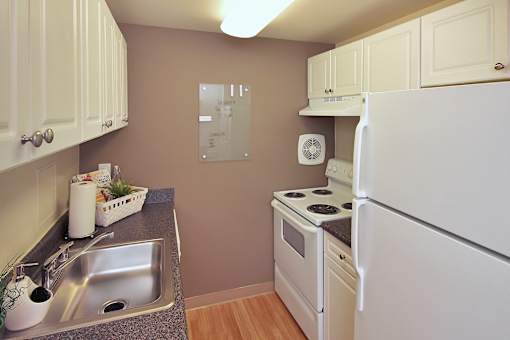 A kitchen with white appliances and wooden cabinets.