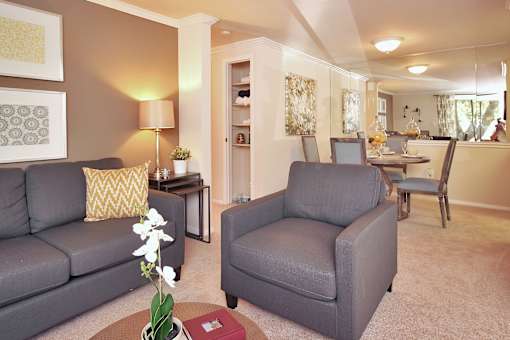 A grey sofa and armchair in a living room with a table and a vase of flowers.