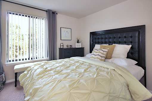 A bed with a yellow comforter and a black headboard.