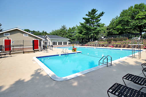 A pool with a diving board and a small building.