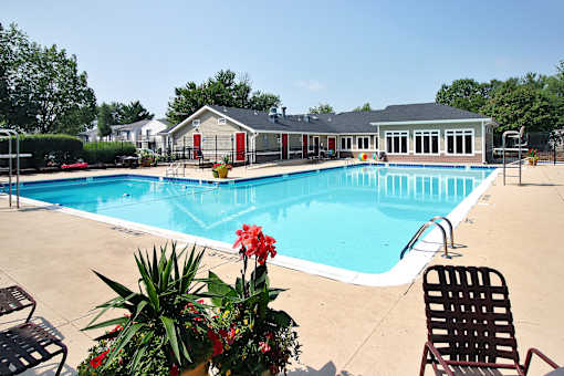 A pool with a chair and a plant in front of a building.