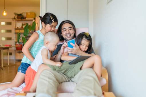A man is reading a book to two children on a couch.