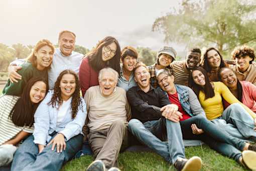 A group of people sitting on the grass in a park.