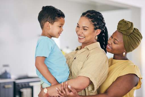 A woman and a child are standing close together, with the woman's arm around the child.