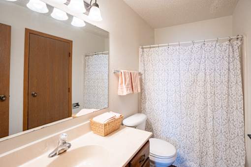 A bathroom with a white sink and a white toilet. Fargo, ND Cedars 4 Apartments