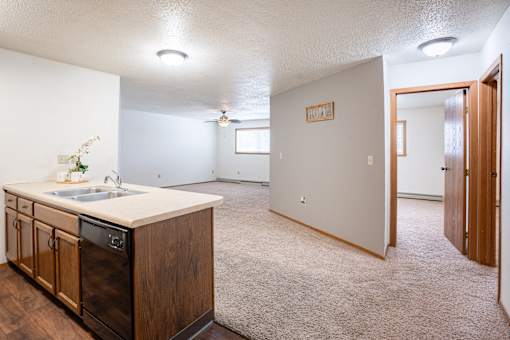 A kitchen with wooden cabinets and a white sink. Fargo, ND Cedars 4 Apartments