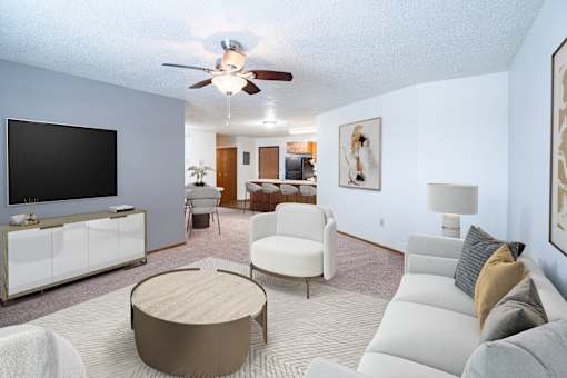 A living room with a white couch, a wooden coffee table, and a flat screen TV. Fargo, ND Cedars 4 Apartments