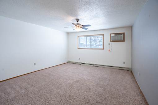 A room with a ceiling fan and a window. Fargo, ND Cedars 4 Apartments