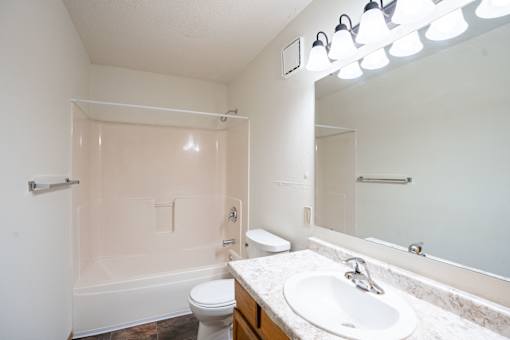 A white bathroom with a toilet, sink, and mirror.