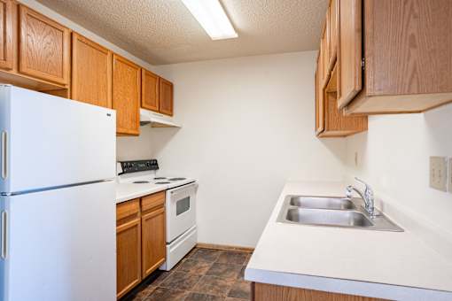 A kitchen with a white refrigerator and wooden cabinets.