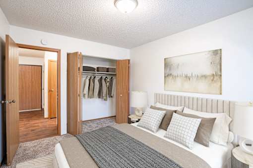 A bedroom with a large bed and a painting on the wall. Fargo, ND Candlelight Apartments