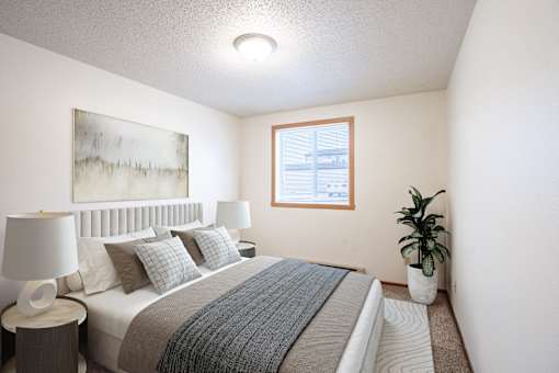 A bedroom with a bed, nightstand, and a plant. Fargo, ND Candlelight Apartments