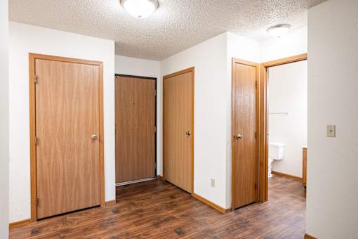 Three wooden doors in a white hallway. Fargo, ND Candlelight Apartment