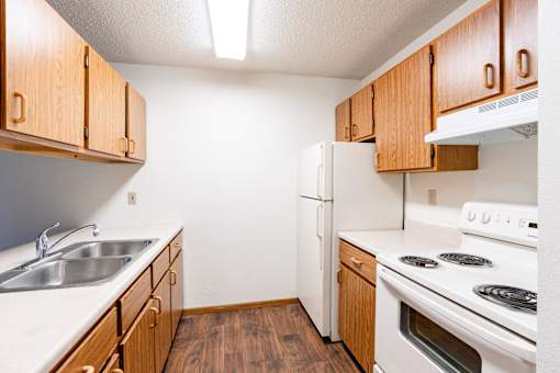 A kitchen with wooden cabinets and white appliances. Fargo, ND Candlelight Apartments