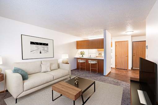 A living room with a couch, coffee table, and a painting on the wall. Fargo, ND Candlelight Apartments