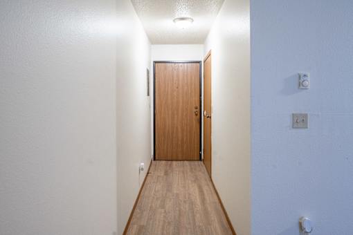 A long hallway with a brown door at the end. Fargo, ND Candlelight Apartments