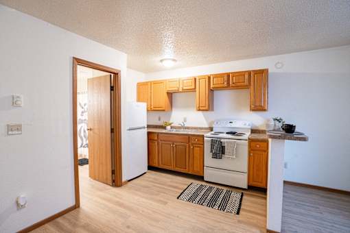 A kitchen with wooden cabinets and a white stove. Fargo, ND Candlelight Apartments