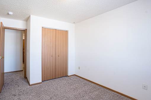 A room with a brown door and carpeted floor. Fargo, ND Country Edge Apartments