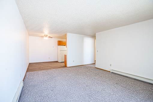 A room with a carpeted floor and a ceiling fan. Fargo, ND Country Edge Apartments