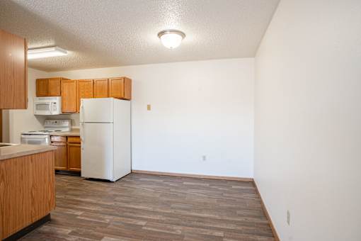 A kitchen with a refrigerator, microwave, and oven.