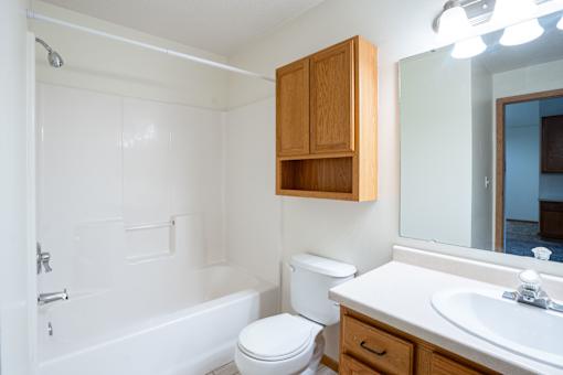 A white bathroom with a toilet, sink, and bathtub. Fargo, ND Summit Point Apartments