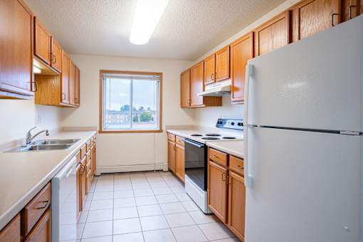 A kitchen with white appliances and wooden cabinets. Fargo, ND Summit Point Apartments