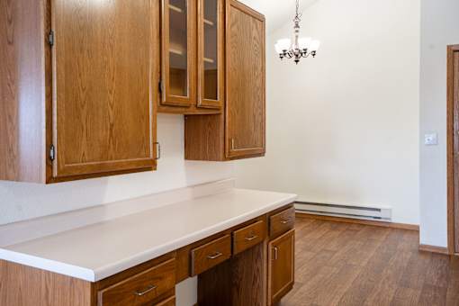 A desk with wooden cabinets and a white countertop. Fargo, ND Somerset Apartments
