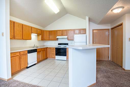 A kitchen with wooden cabinets and white appliances. Fargo, ND Summit Point Apartments