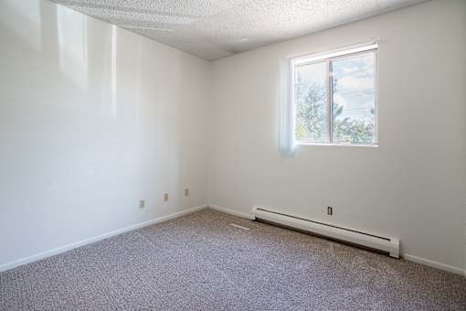 A room with a window and a radiator on the floor. Bismarck, ND Belmont Apartments