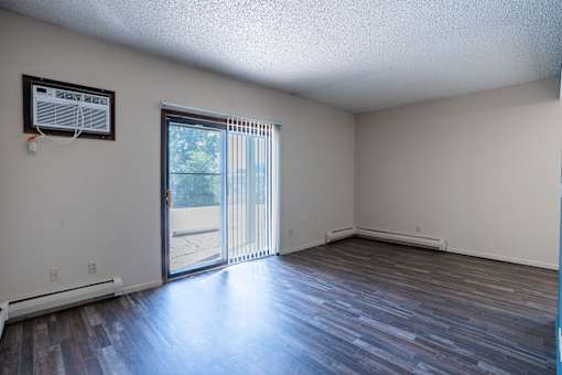 A room with a sliding glass door leading to a patio. Bismarck, ND Belmont Apartments