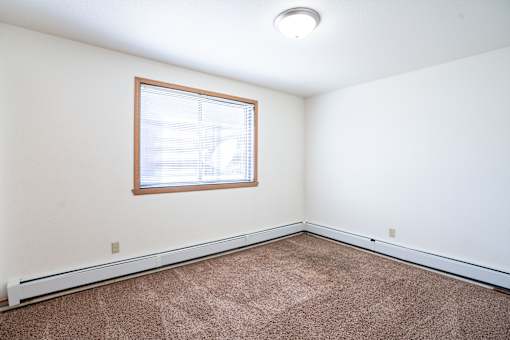 A room with a window and carpeted floor. Fargo, ND Birchwood 2 Apartments