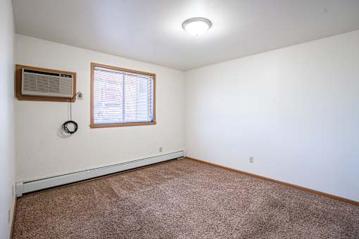 A room with a window and a carpet on the floor. Fargo, ND Birchwood 2 Apartments