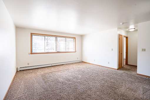 A room with a window and carpeted floor. Fargo, ND Birchwood 2 Apartments