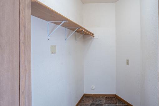 A white wall with a brown shelf and hooks. Dilworth, MN Fieldstone Apartments