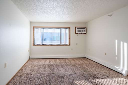 A room with a window and a carpet on the floor. Dilworth, MN Fieldstone Apartments