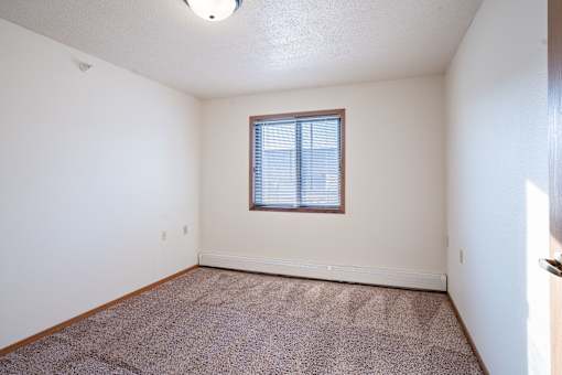 A room with a window and carpeted floor. Dilworth, MN Fieldstone Apartments