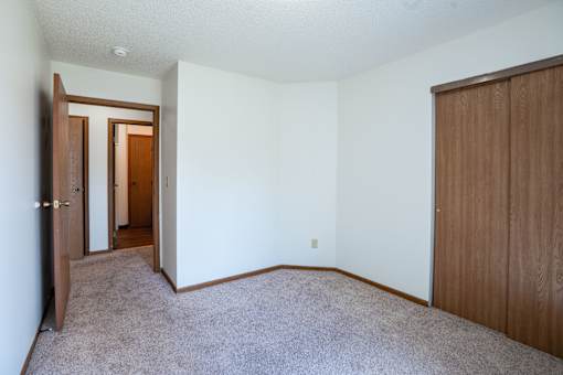 A room with a carpeted floor and two wooden doors.
