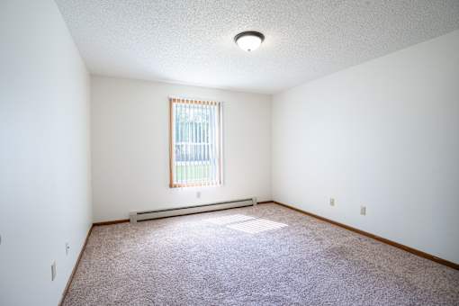 A room with a window and a carpeted floor.