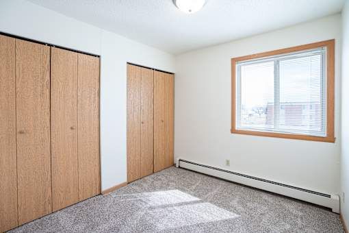 A room with a window and a carpeted floor. West Fargo, ND Saddlebrook Apartments