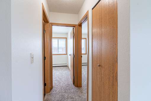 A hallway with two doors on either side leading to other rooms. West Fargo, ND Saddlebrook Apartments