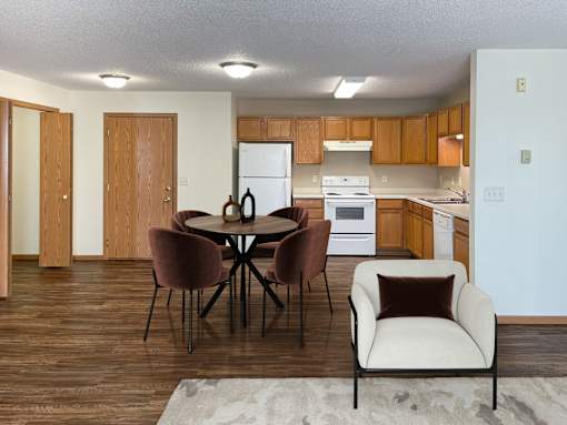 A kitchen with a table and chairs in the foreground. Bismarck, ND Sierra Ridge Apartments