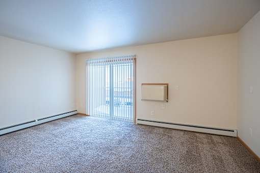 A room with a carpeted floor and a window with blinds. Moorhead, MN Sandy Creek Apartments