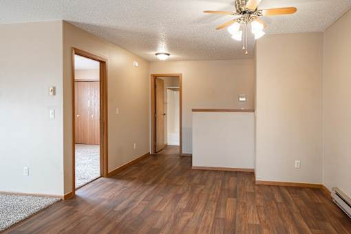 A room with a ceiling fan and wooden floors.