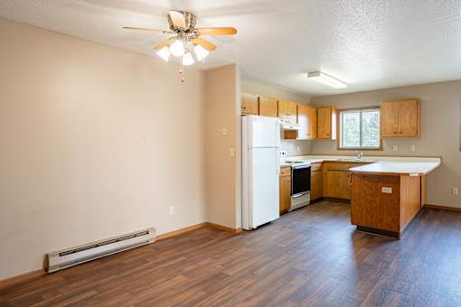 A kitchen with wooden floors and a ceiling fan.