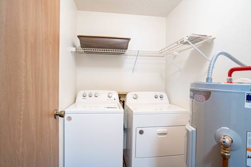 A small laundry room with a washer and dryer and a clothes drying rack.