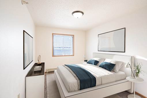 A bedroom with a large bed and a window. Fargo, ND Fieldstone Apartments