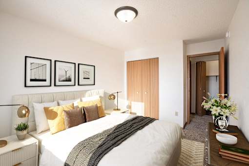 A bedroom with a large bed and a wooden door. Fargo, ND Fieldstone Apartments